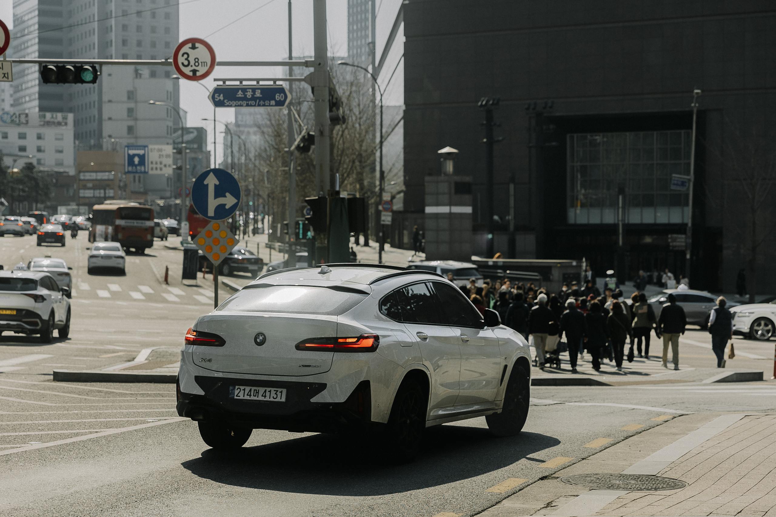 A car driving down a city street with people walking