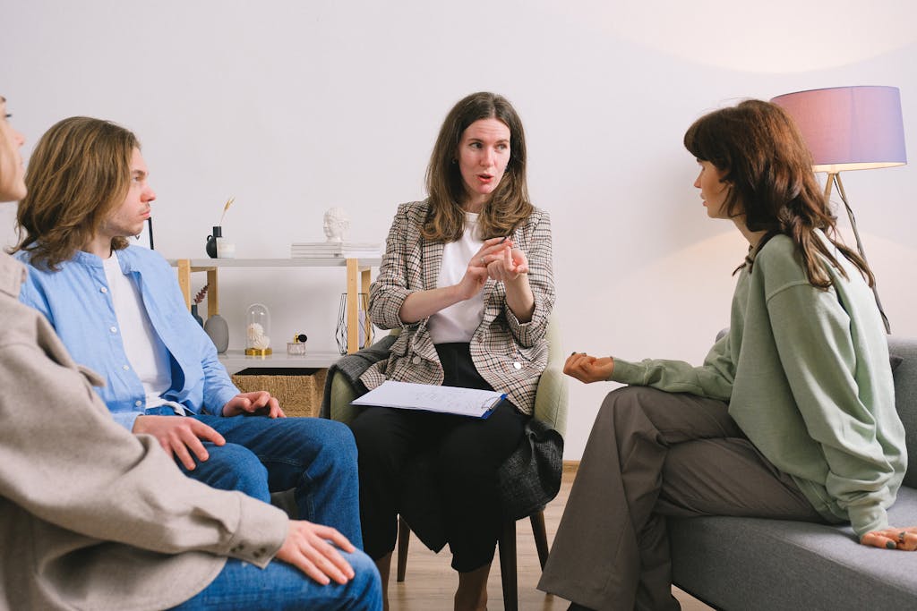 Female therapist during group session talking to female patients gathering in light cozy office