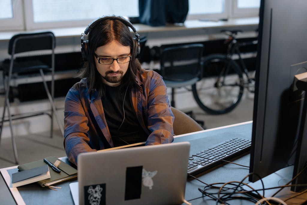 Man Sitting at the Desk in an Office and Using a Computer